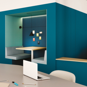 Espace de bureau moderne avec un ordinateur portable sur une table, des stylos colorés et un stand confortable orné de notes autocollantes sur le mur. Des lampes suspendues élégantes sont suspendues au plafond, ajoutant une touche élégante à cet espace de travail dynamique.